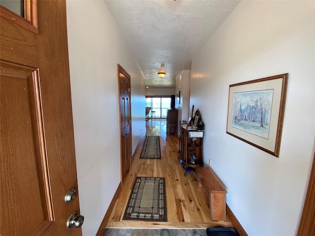 hallway featuring light hardwood / wood-style floors and a textured ceiling