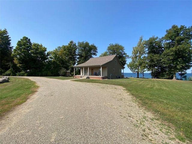 view of front of home featuring covered porch, a water view, and a front lawn