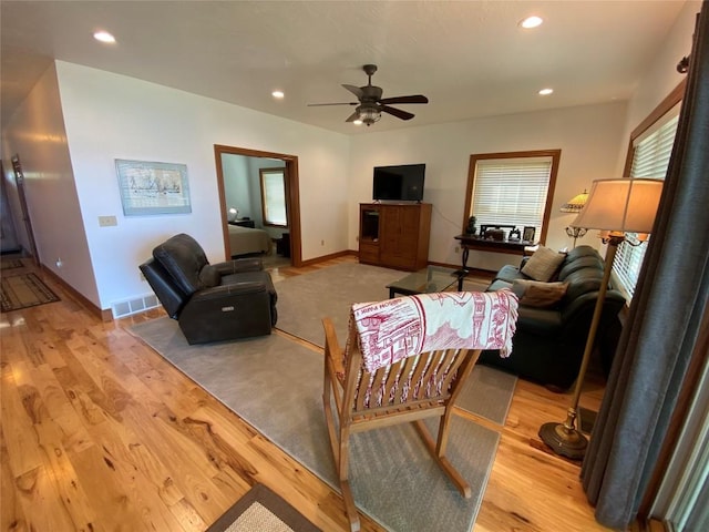 living room featuring light hardwood / wood-style flooring and ceiling fan