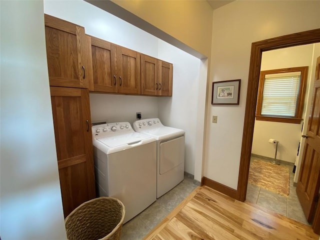 washroom featuring washer and clothes dryer, light tile patterned flooring, and cabinets