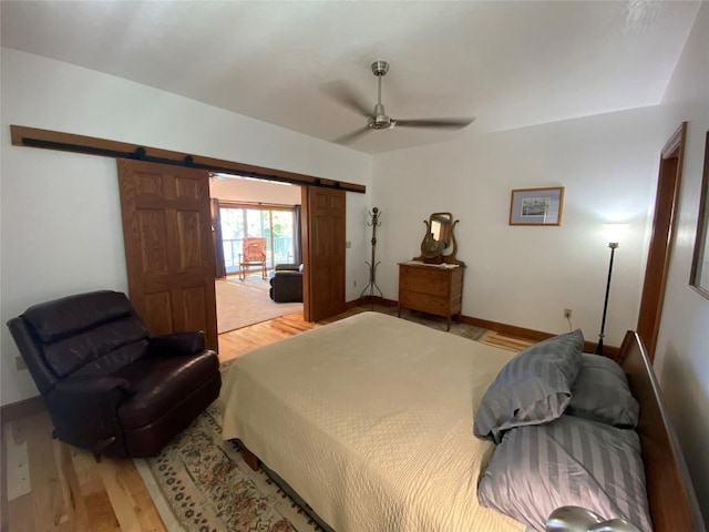 bedroom with hardwood / wood-style floors, a barn door, and ceiling fan