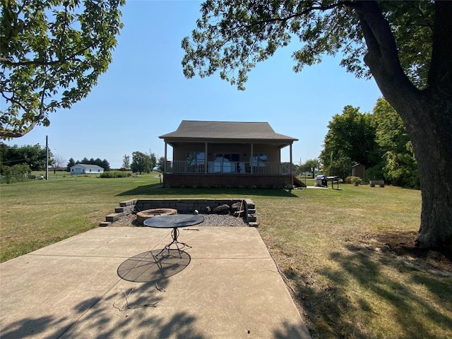 rear view of property with a patio area, a yard, covered porch, and an outdoor fire pit