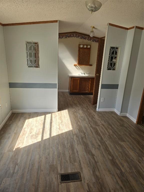 interior space with visible vents, a textured ceiling, and wood finished floors