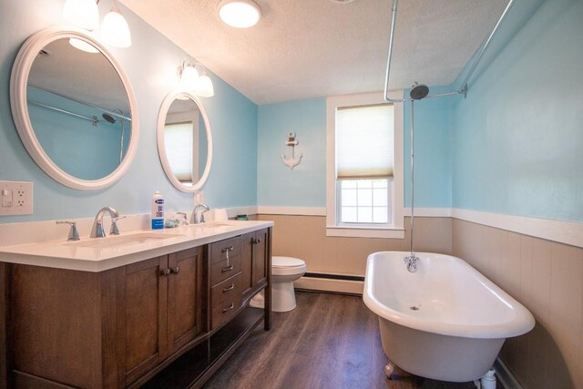 5499 Pinetree Rd, Mckean, PA 16426 - bathroom featuring wainscoting, a textured ceiling, a baseboard heating unit, wood finished floors, and a freestanding bath