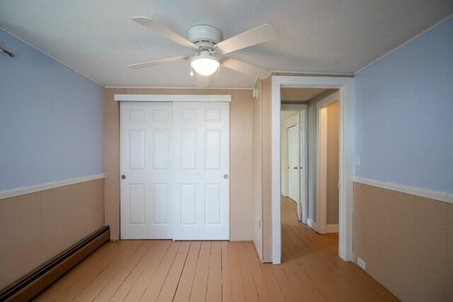 5499 Pinetree Rd, Mckean, PA 16426 - unfurnished bedroom with a baseboard heating unit, light wood-type flooring, a closet, and a ceiling fan