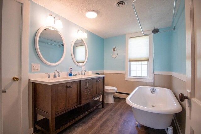 5499 Pinetree Rd, Mckean, PA 16426 - full bath featuring a textured ceiling, wood finished floors, a freestanding bath, a wainscoted wall, and double vanity