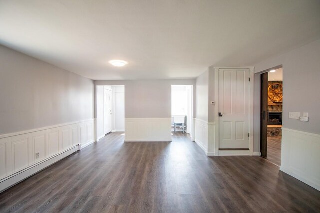 5499 Pinetree Rd, Mckean, PA 16426 - unfurnished room with a baseboard heating unit, a wainscoted wall, dark wood-style flooring, and a decorative wall