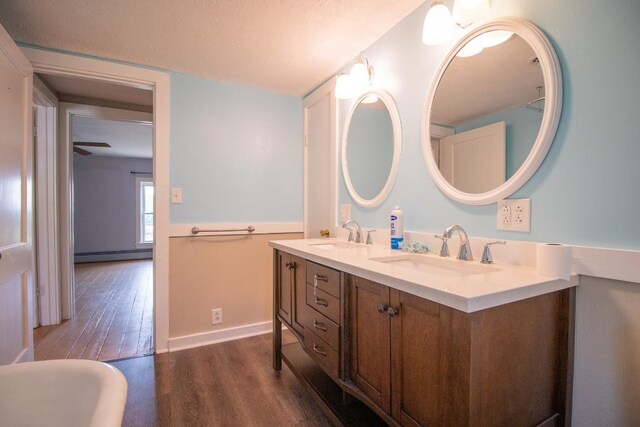 5499 Pinetree Rd, Mckean, PA 16426 - bathroom with a baseboard heating unit, wood finished floors, double vanity, and a textured ceiling
