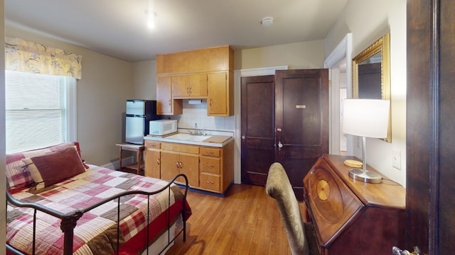 kitchen with sink, light hardwood / wood-style flooring, and tasteful backsplash