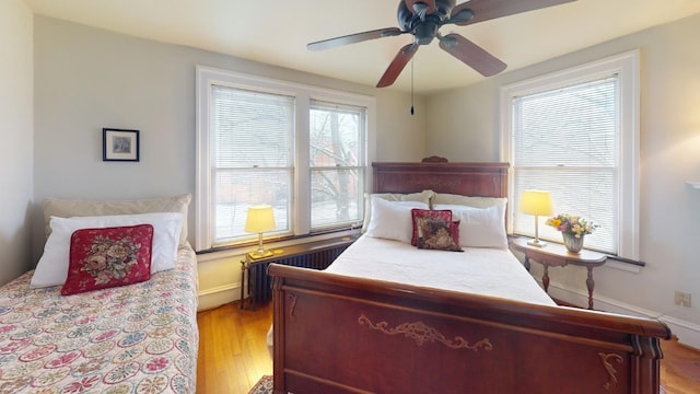 bedroom featuring radiator, light hardwood / wood-style flooring, and ceiling fan