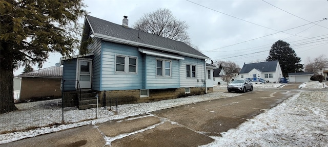 view of side of property featuring entry steps, roof with shingles, and a chimney