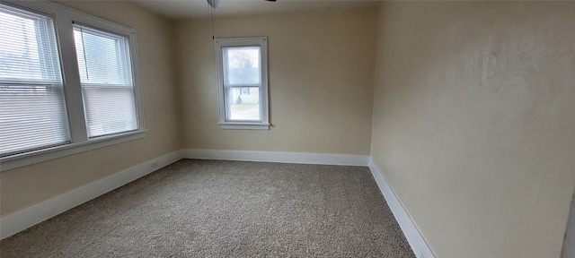 carpeted spare room featuring a ceiling fan and baseboards