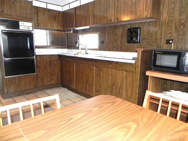 kitchen featuring black appliances, light tile patterned floors, light countertops, and a sink