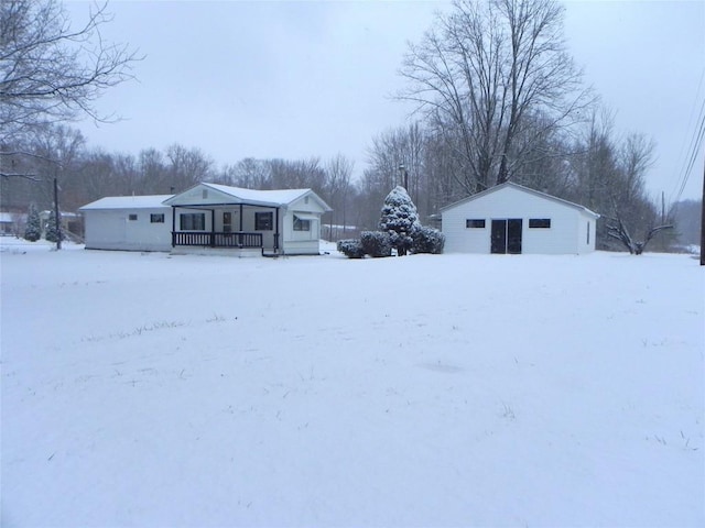 snowy yard with a porch and an outbuilding