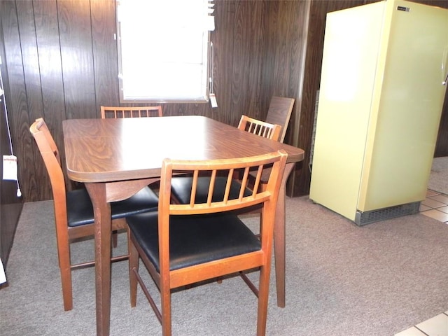 dining room featuring wooden walls and light colored carpet