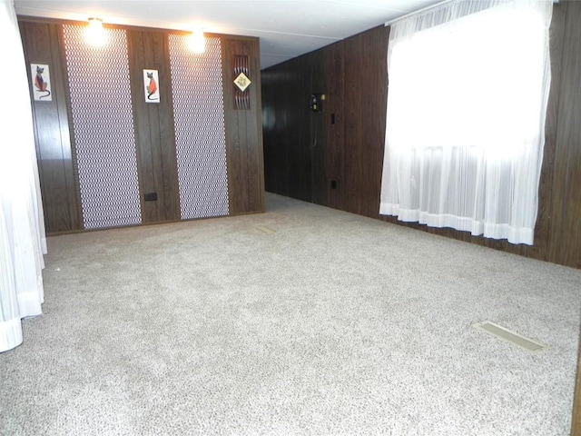 carpeted spare room featuring wood walls