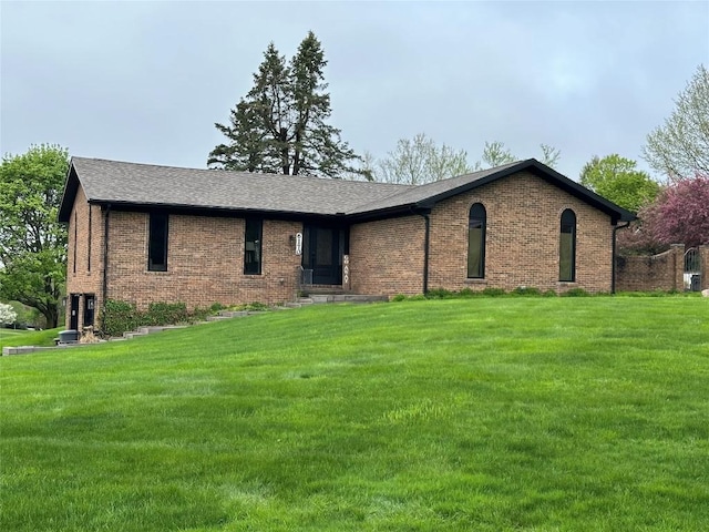 ranch-style house featuring a front lawn, brick siding, and roof with shingles
