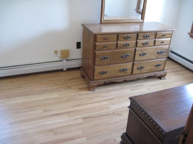 bedroom with light hardwood / wood-style flooring and a baseboard heating unit