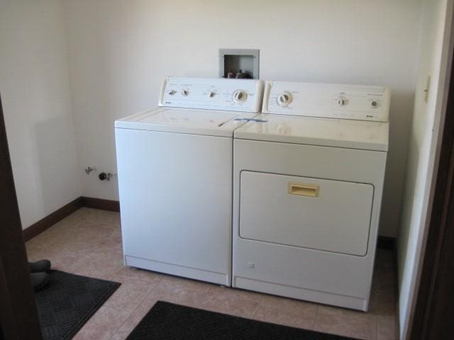 clothes washing area featuring washing machine and dryer and light tile patterned flooring