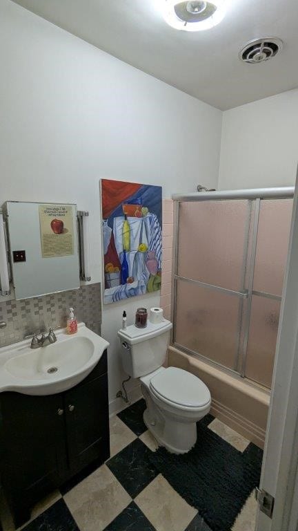 full bathroom featuring bath / shower combo with glass door, vanity, backsplash, and toilet