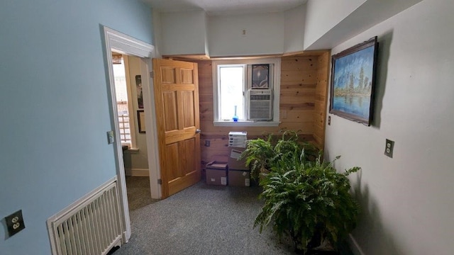 hall featuring cooling unit, wooden walls, and carpet floors