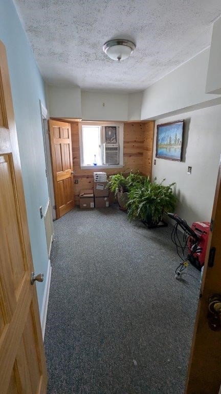 misc room featuring dark carpet, cooling unit, and a textured ceiling