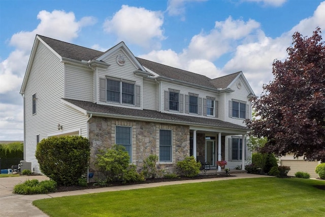 6018 Pebble Creek Dr, Fairview, PA 16415 - view of front of house with a front yard, stone siding, a shingled roof, and a porch
