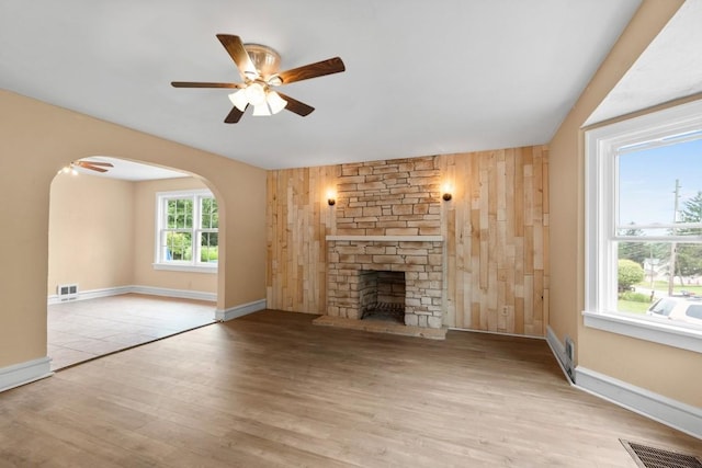 20527 Baird Rd, Meadville, PA 16335 - unfurnished living room featuring a ceiling fan, a fireplace, wood finished floors, arched walkways, and wooden walls