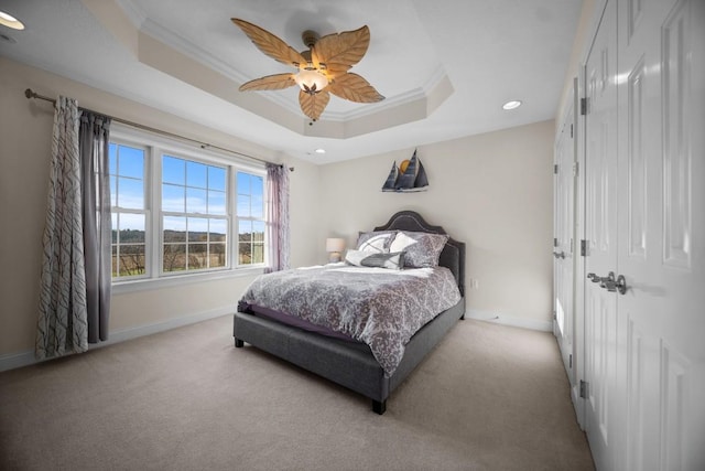 bedroom with a raised ceiling, ceiling fan, crown molding, and light carpet