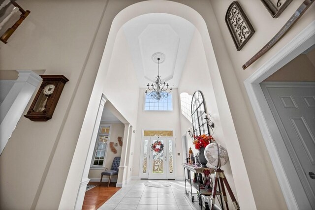 tiled entrance foyer with a chandelier and a towering ceiling