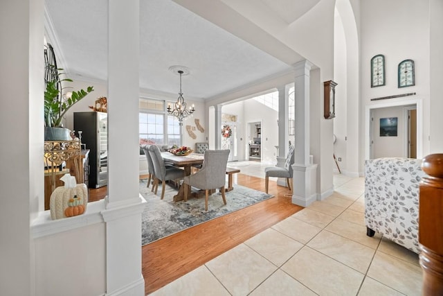 dining area with a chandelier, crown molding, light hardwood / wood-style flooring, and decorative columns