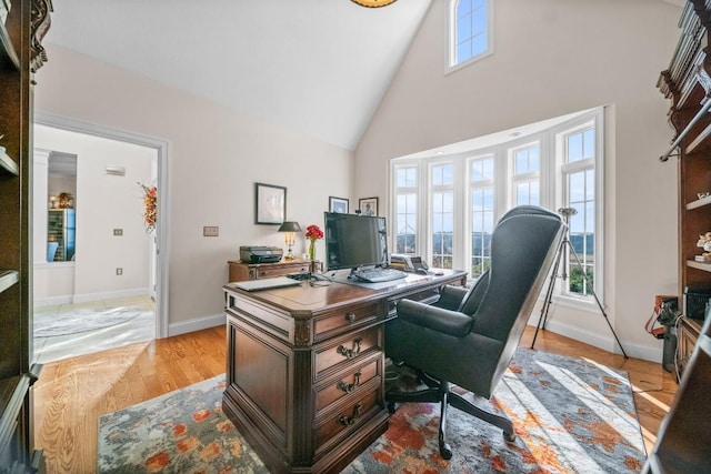 office space with light hardwood / wood-style floors and high vaulted ceiling