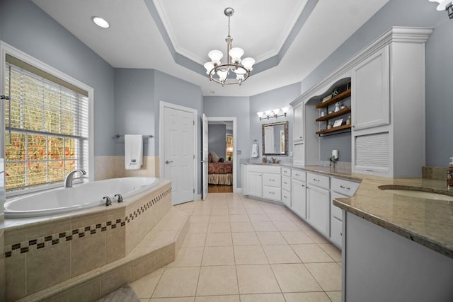 bathroom featuring tile patterned floors, vanity, a raised ceiling, tiled tub, and a notable chandelier