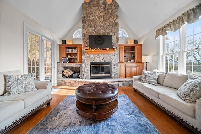 living room featuring a stone fireplace, a wealth of natural light, and dark hardwood / wood-style floors