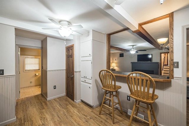 454 Orchard Beach Rd, North East, PA 16428 - kitchen featuring ceiling fan, a kitchen bar, wood finished floors, wainscoting, and white cabinets