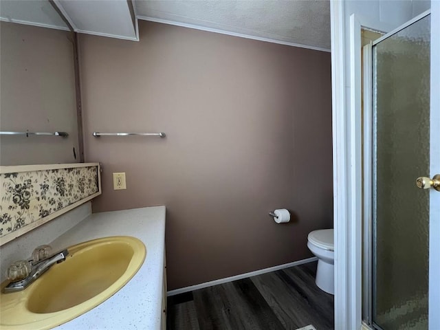 bathroom featuring hardwood / wood-style floors, toilet, a shower with door, vanity, and ornamental molding