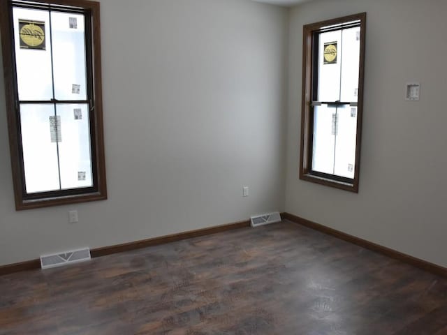 unfurnished room with a wealth of natural light, visible vents, and baseboards