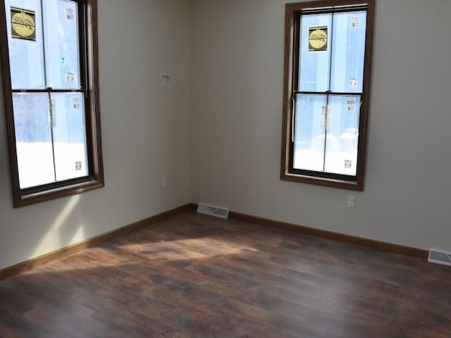 empty room featuring baseboards, visible vents, and dark wood finished floors