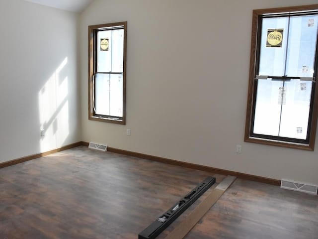 unfurnished room featuring baseboards, visible vents, and wood finished floors