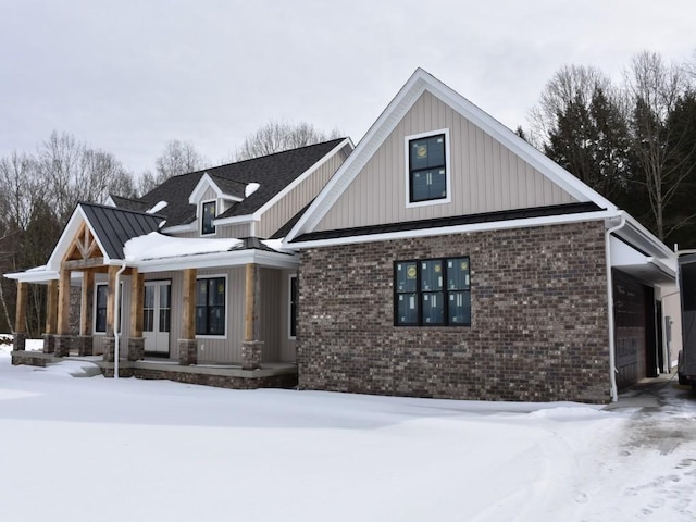 view of front of house featuring covered porch, a standing seam roof, metal roof, and brick siding