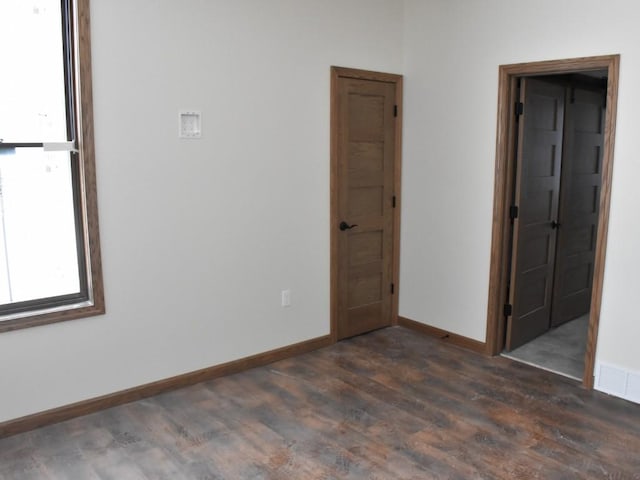 unfurnished room with dark wood-style floors, visible vents, and baseboards