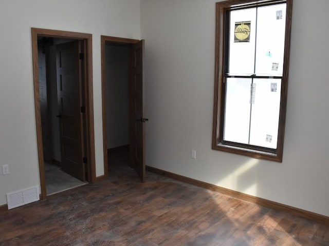 unfurnished bedroom with wood finished floors, visible vents, baseboards, and multiple windows