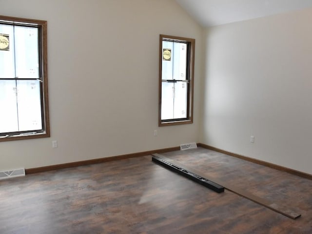 unfurnished room with lofted ceiling, visible vents, a wealth of natural light, and wood finished floors