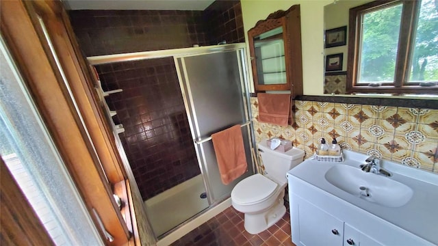 bathroom featuring backsplash, vanity, a shower with door, tile patterned flooring, and toilet