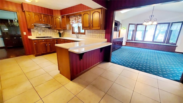 kitchen featuring gas cooktop, backsplash, kitchen peninsula, pendant lighting, and lofted ceiling