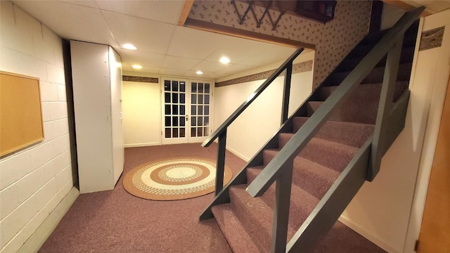 stairs featuring a paneled ceiling and carpet flooring