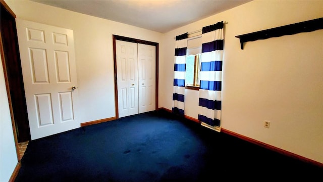 unfurnished bedroom featuring dark colored carpet and a closet