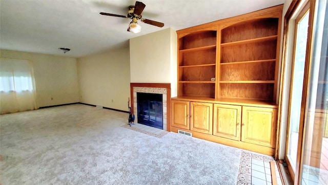 unfurnished living room featuring a tiled fireplace, ceiling fan, and light carpet