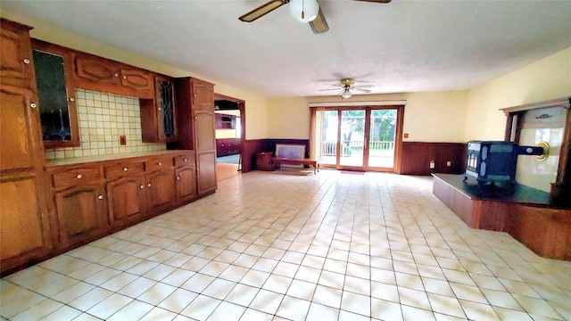 kitchen with ceiling fan, a wood stove, and wooden walls