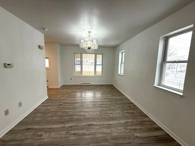 unfurnished room with a baseboard radiator, dark hardwood / wood-style floors, and a chandelier